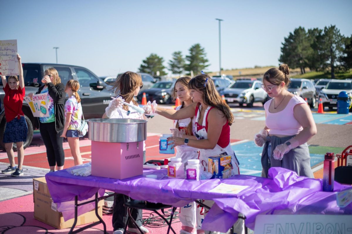 Environmental Club seniors Hailey Blackmon, Elizabeth Marie Daggers, Katherine Issler and Ayla Piro make cotton candy at Tailgate, 2024. Photo by Zachary Closser.
