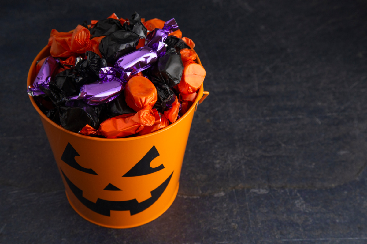 A Halloween jack-o-lantern bucket filled with candy. Photo from Canva.com.