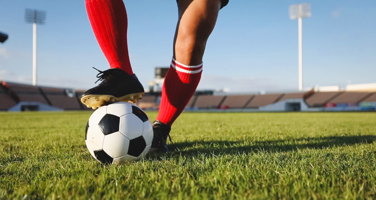 Soccer player dribbling a soccer ball. Photo by Canva.com. 
