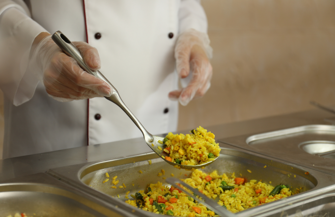 Image of a cafeteria worker serving food. Photo from Canva.com