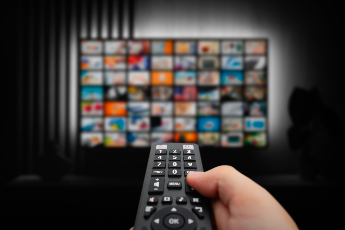 A person holding a remote control picking a show to watch. Photo from Canva.com.