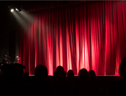 Photo of a theatre stage with the spotlight on it. Photo courtesy of Canva.com.