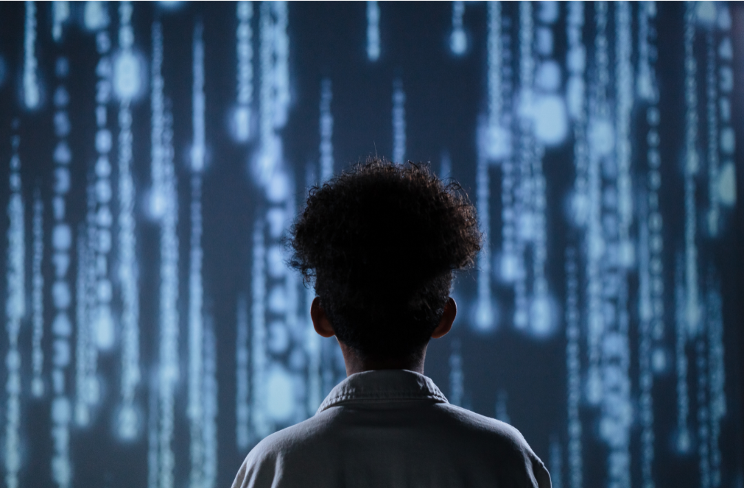 Person facing a wall of technology. Photo courtesy of Canva.com.