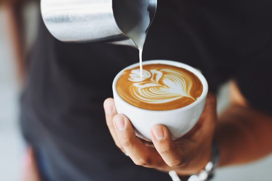 Image of creamer poured into design over coffee. Photo by Adobe Stock.
